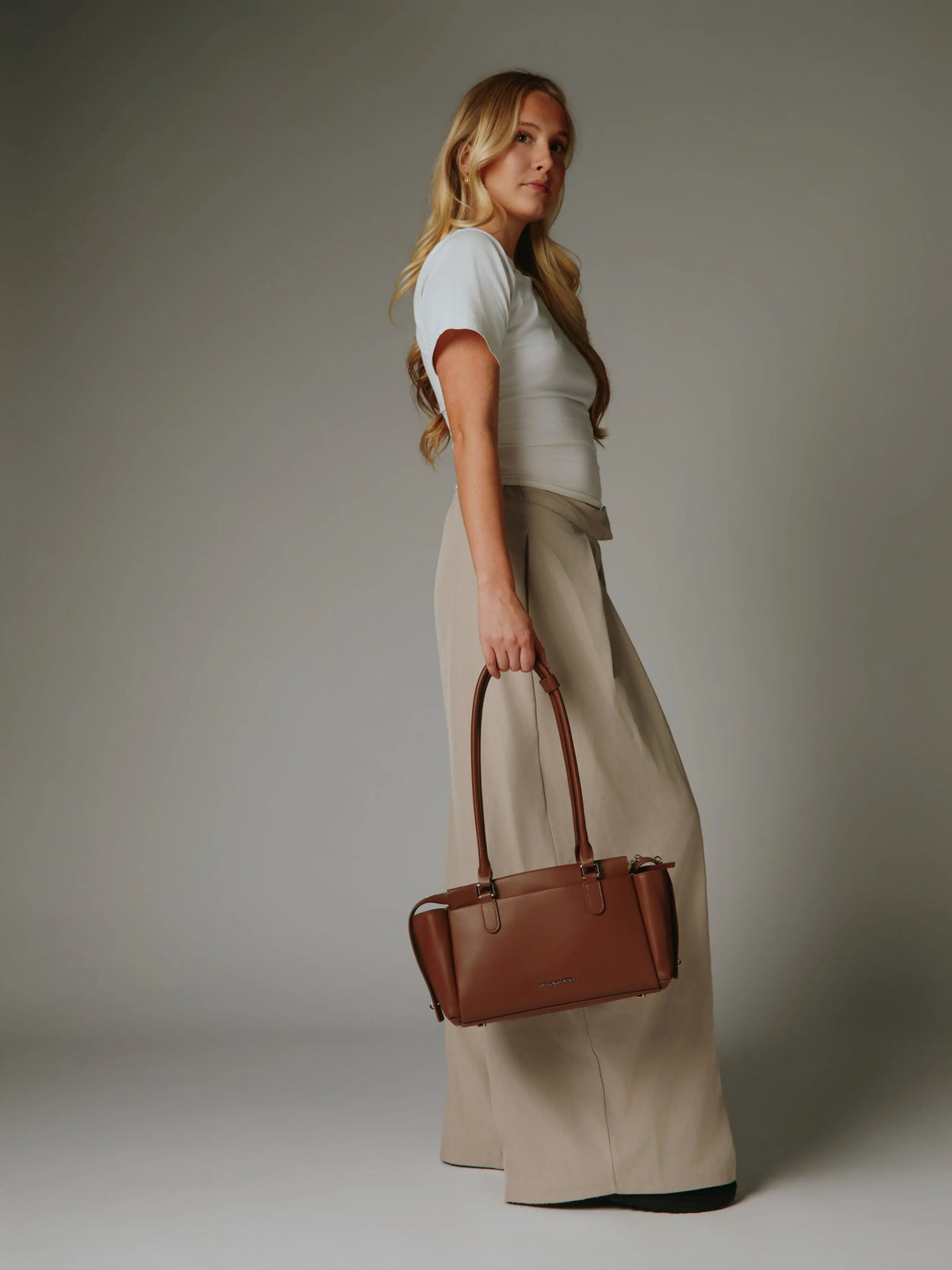 Woman holding a brown handbag with stylish posture.
