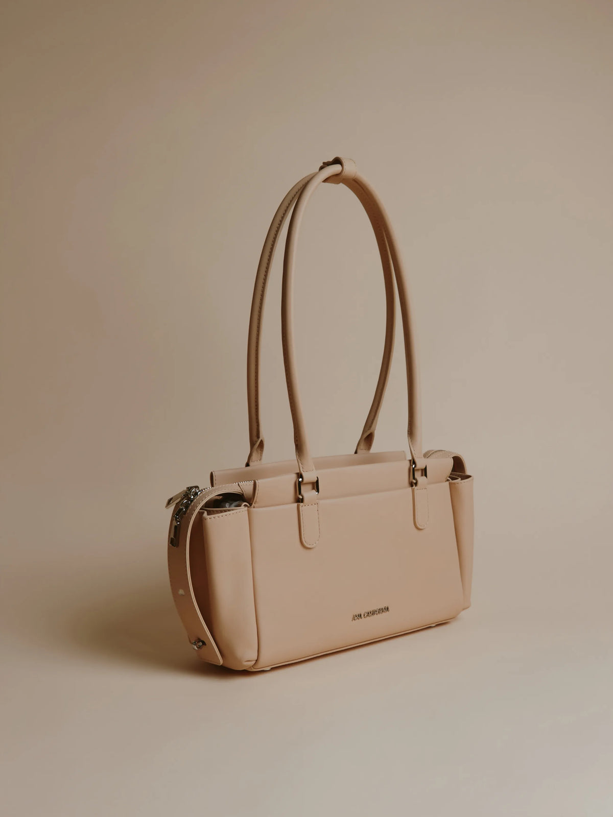 Ivory handbag shown from the side with a smooth finish.
