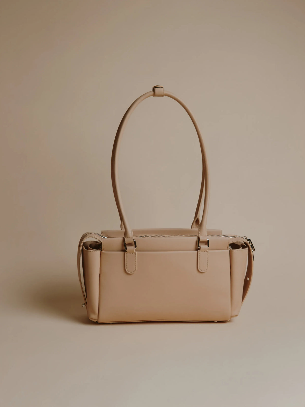 Close-up of ivory handbag showcasing zippers.