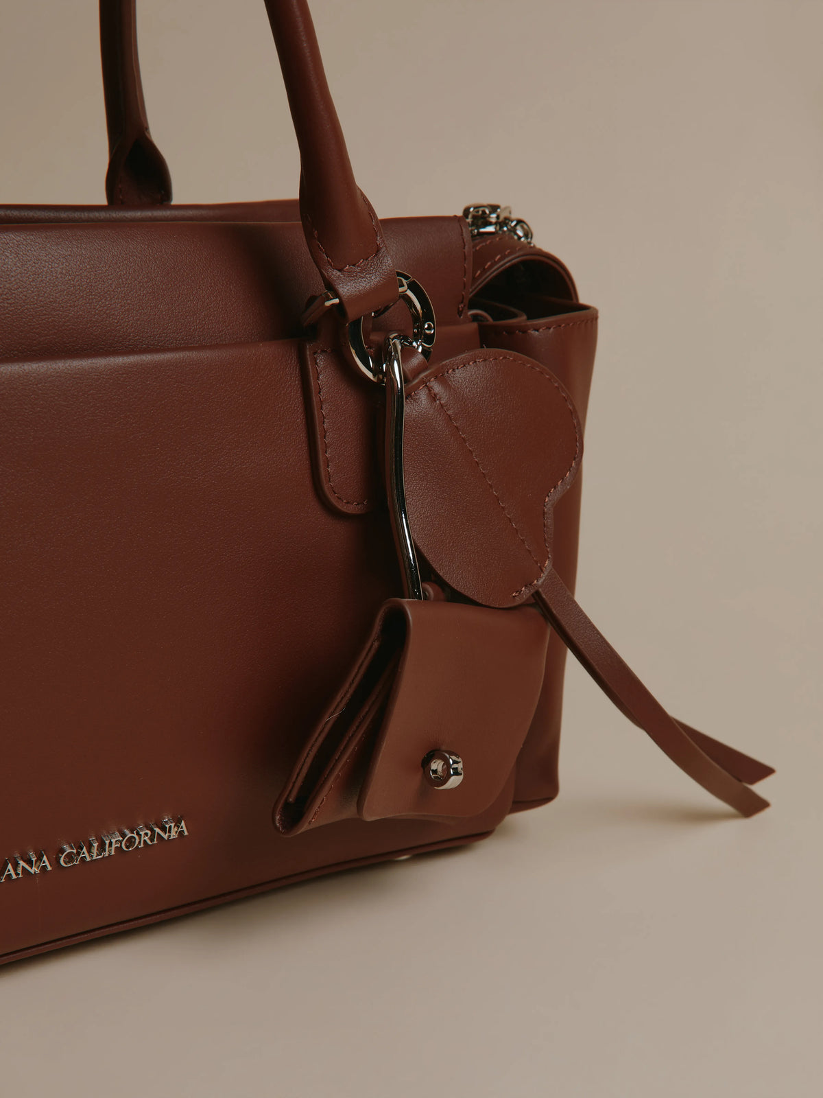 Brown handbag with two long handles facing forward.
