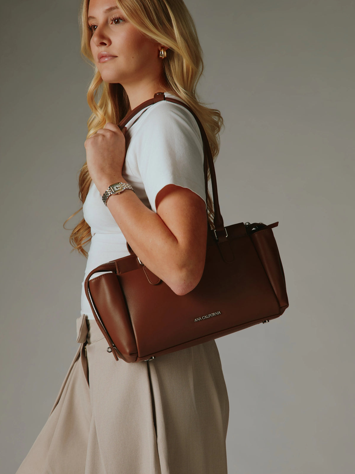 Close-up of the brown handbag showing the charm detail.