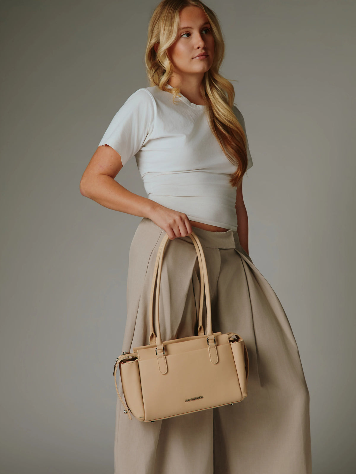 Ivory handbag displayed upright with long handles.