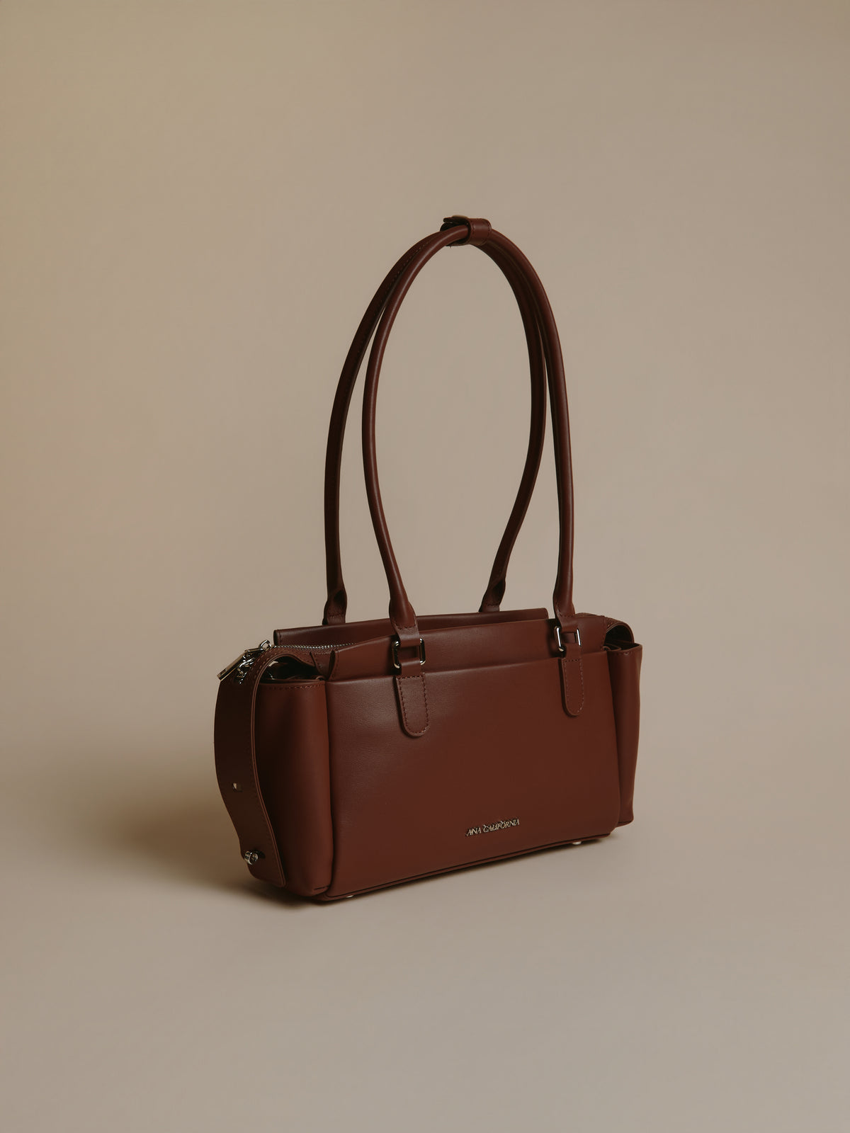 Brown handbag shown from the side with long handles.